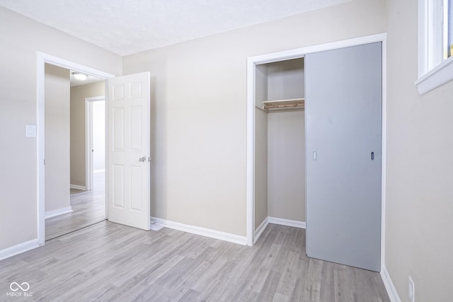 unfurnished bedroom with a closet and light hardwood / wood-style floors