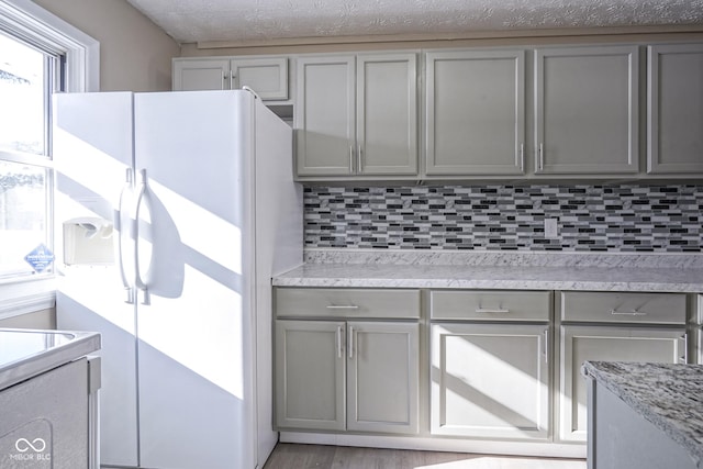 kitchen featuring tasteful backsplash, white fridge with ice dispenser, and gray cabinets