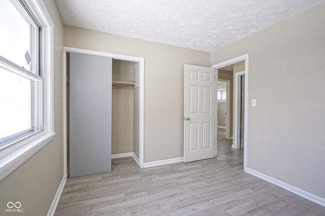 unfurnished bedroom with a textured ceiling, a closet, and light hardwood / wood-style floors