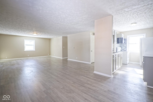 spare room with a textured ceiling and light hardwood / wood-style floors