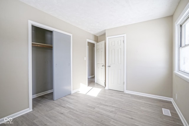 unfurnished bedroom featuring multiple windows and light hardwood / wood-style floors