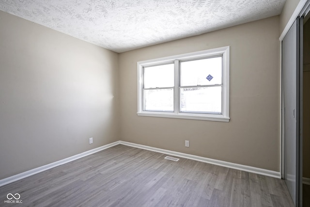 empty room featuring wood-type flooring and a textured ceiling