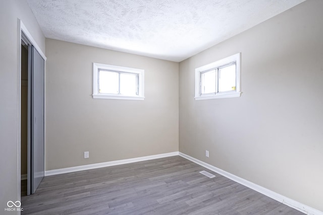 spare room with hardwood / wood-style flooring, plenty of natural light, and a textured ceiling