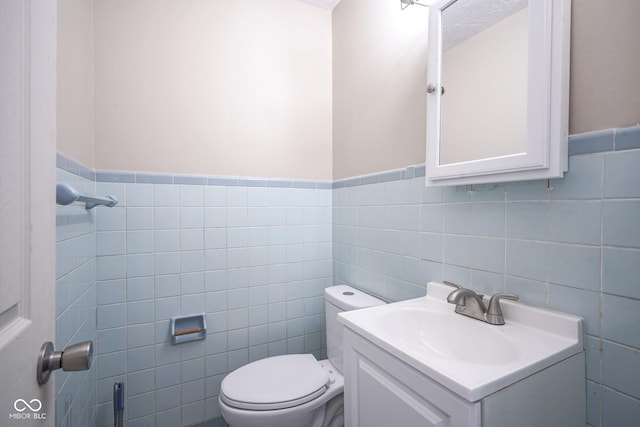 bathroom featuring tile walls, toilet, and vanity