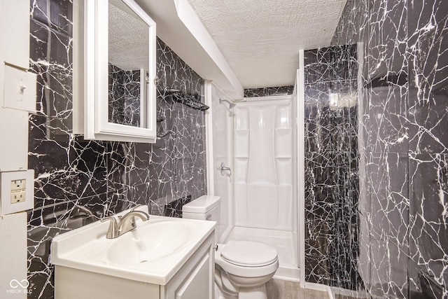 bathroom with a textured ceiling, toilet, a shower, and vanity