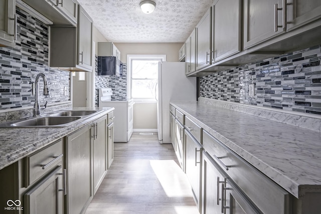 kitchen with tasteful backsplash, white appliances, a textured ceiling, light hardwood / wood-style flooring, and sink