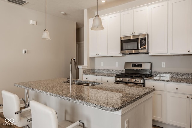 kitchen with stainless steel appliances, sink, decorative light fixtures, a breakfast bar area, and a center island with sink