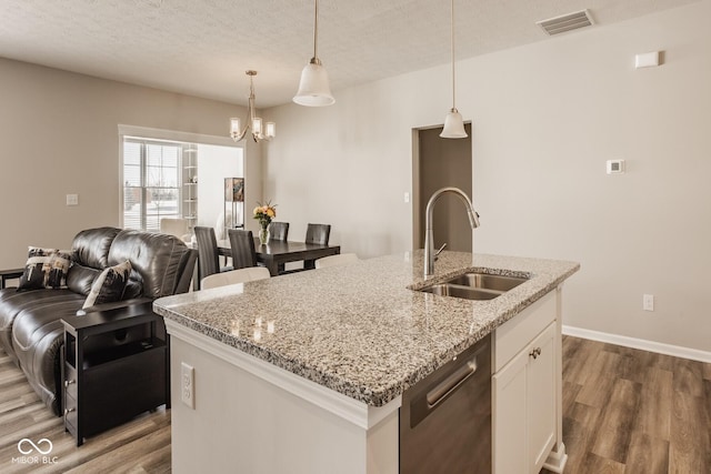 kitchen with a center island with sink, pendant lighting, sink, white cabinetry, and stainless steel dishwasher