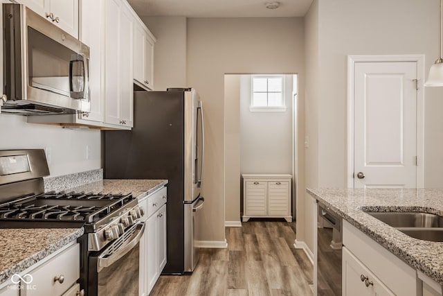 kitchen featuring stainless steel appliances, white cabinetry, and light stone counters