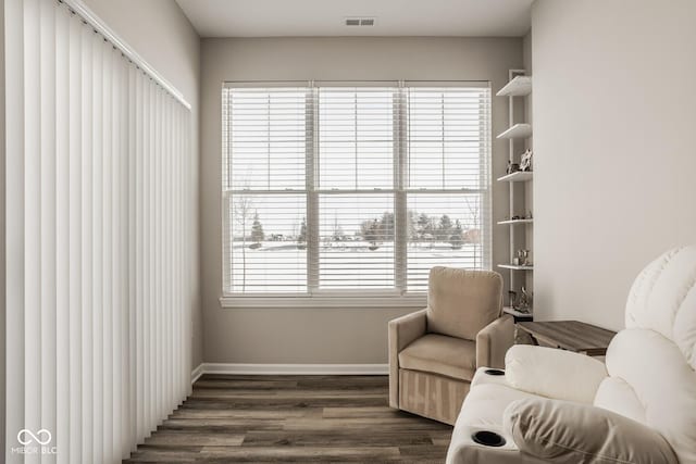 sitting room with dark wood-type flooring and plenty of natural light