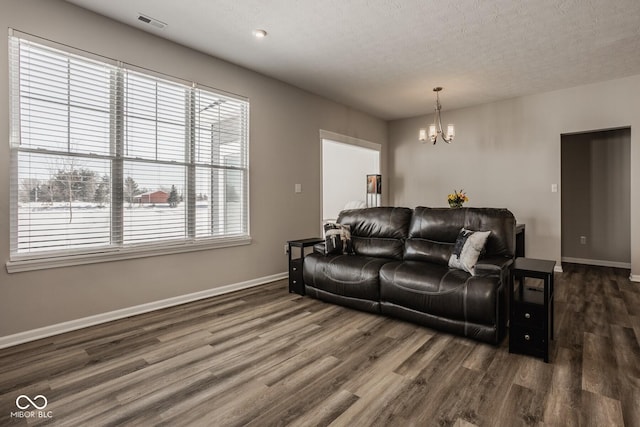 living room with dark wood-type flooring, a textured ceiling, and a chandelier