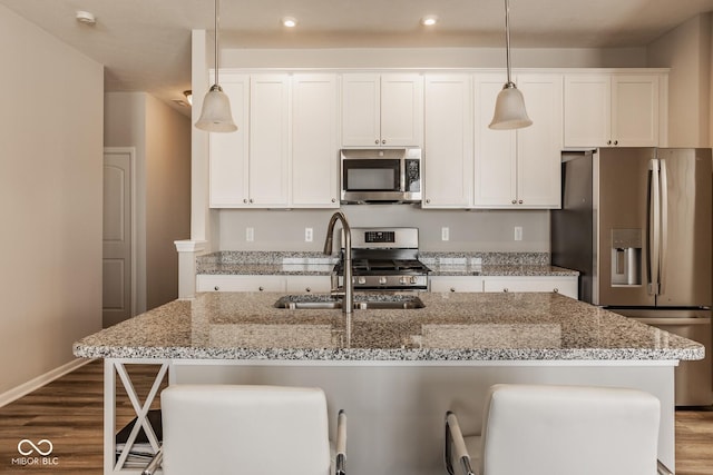 kitchen with sink, a center island with sink, hanging light fixtures, and appliances with stainless steel finishes