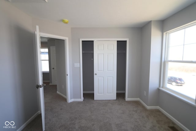 unfurnished bedroom featuring a closet, baseboards, and carpet flooring