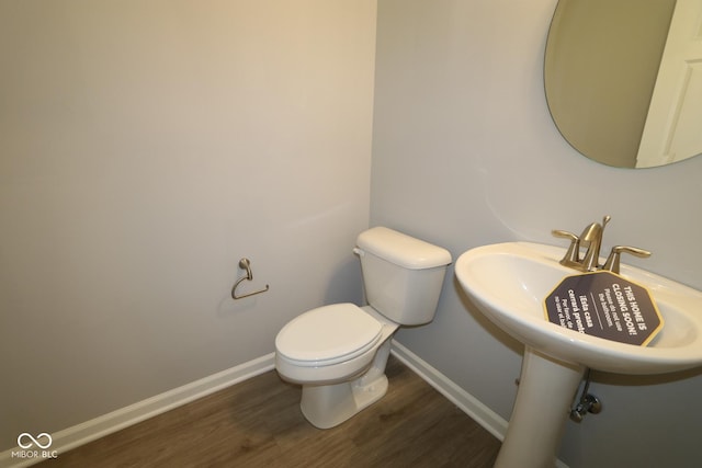 half bath featuring toilet, wood finished floors, and baseboards