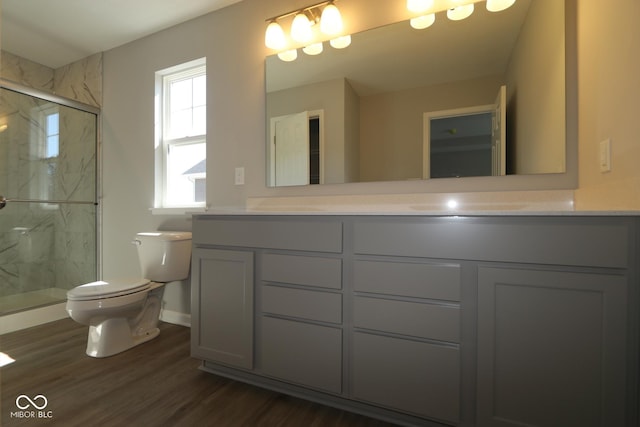 bathroom featuring a marble finish shower, double vanity, toilet, and wood finished floors