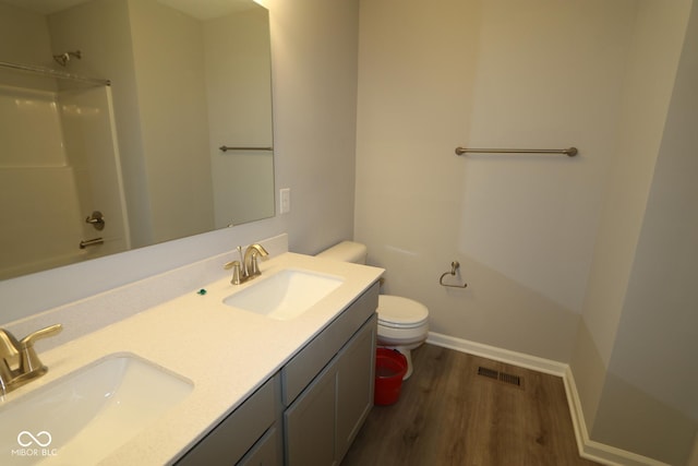 bathroom with toilet, wood finished floors, visible vents, and a sink