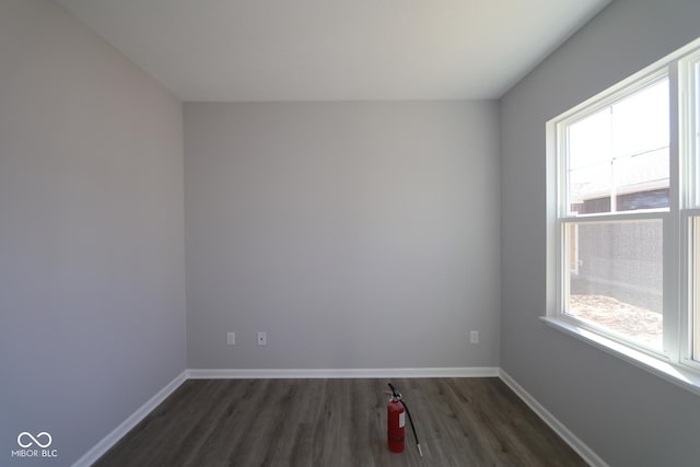 spare room with baseboards and wood finished floors