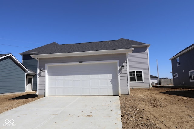 ranch-style house featuring a garage, driveway, and roof with shingles