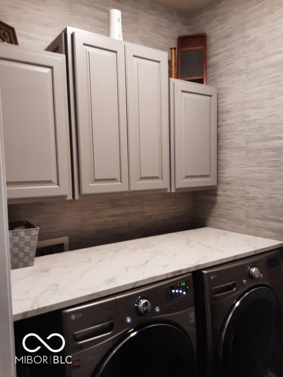 washroom with washing machine and dryer and cabinets