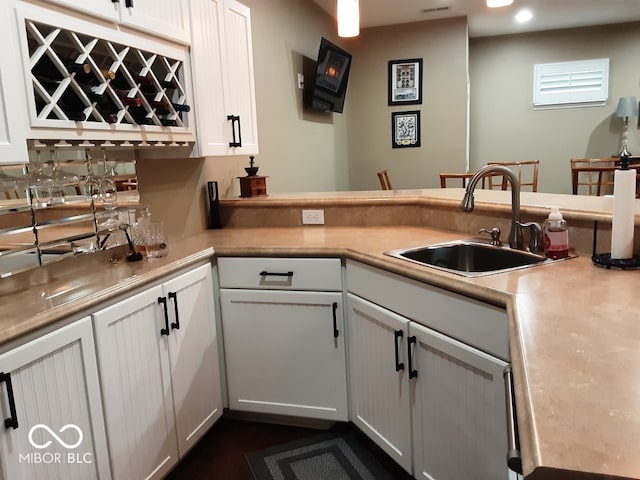 kitchen featuring kitchen peninsula, white cabinetry, and sink