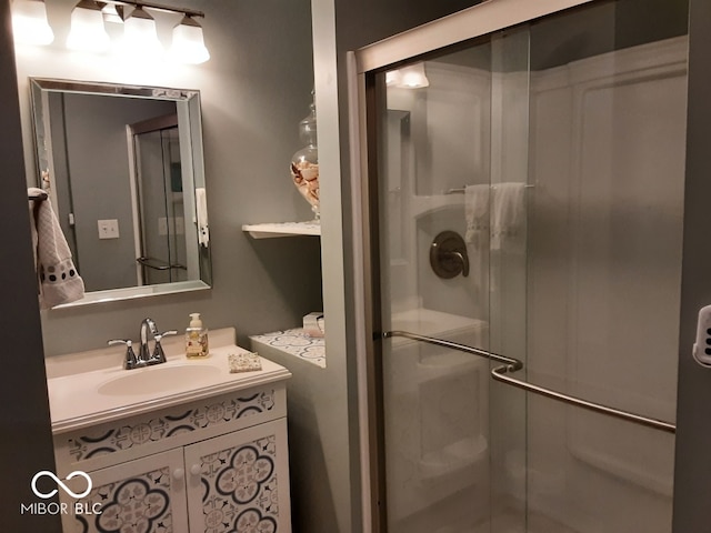 bathroom featuring a shower with door and vanity