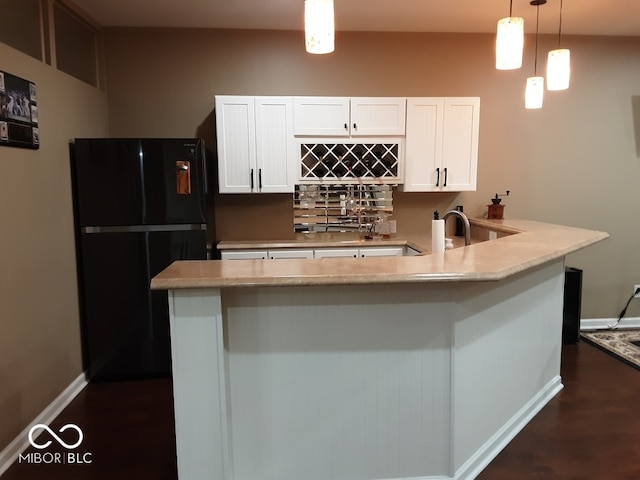 kitchen with black refrigerator, pendant lighting, dark hardwood / wood-style floors, sink, and white cabinetry