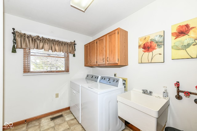 washroom featuring washing machine and dryer, sink, and cabinets