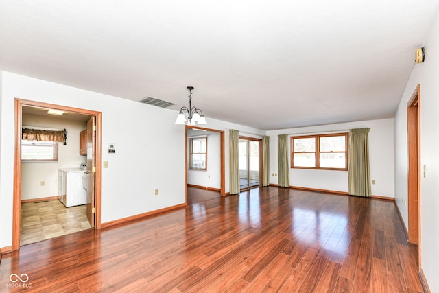 unfurnished room with washer and clothes dryer, hardwood / wood-style flooring, and a notable chandelier