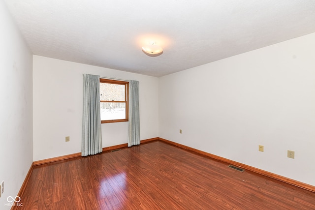 unfurnished room with dark wood-type flooring