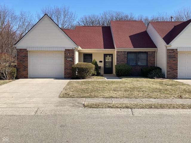 view of front of property featuring a front yard, a garage, brick siding, and driveway