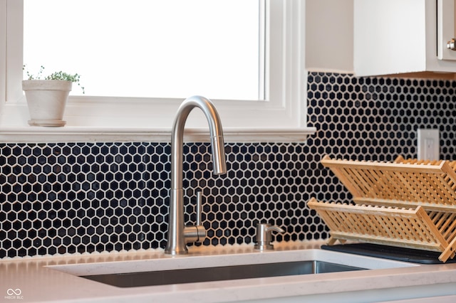 room details featuring decorative backsplash, sink, and white cabinets