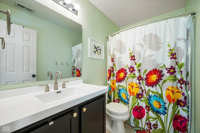 bathroom with vanity, toilet, and a textured ceiling