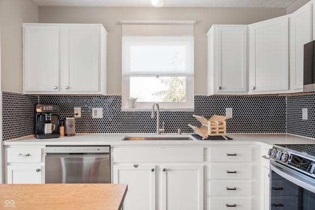 kitchen with sink, backsplash, white cabinets, and appliances with stainless steel finishes