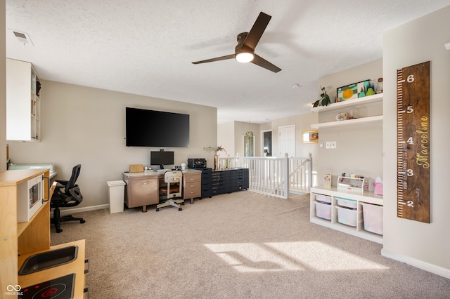 home office with ceiling fan, a textured ceiling, and light carpet