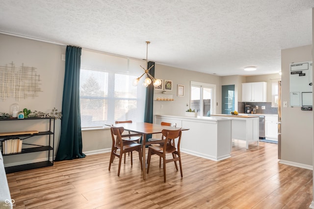 dining space featuring light wood-type flooring and a textured ceiling