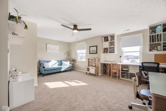 carpeted office with plenty of natural light, a textured ceiling, and ceiling fan