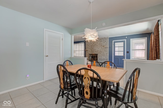 tiled dining room featuring a fireplace and an inviting chandelier