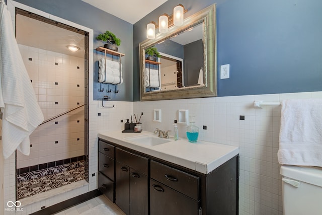 bathroom featuring vanity, toilet, tile walls, and a tile shower