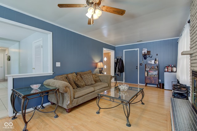 living room featuring ceiling fan, light hardwood / wood-style flooring, and a brick fireplace