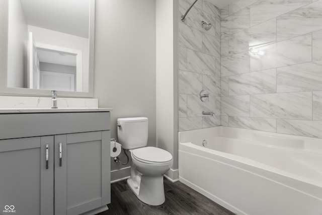 full bathroom with hardwood / wood-style flooring, tiled shower / bath combo, toilet, and vanity