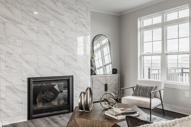 living room with hardwood / wood-style floors, crown molding, and a tiled fireplace