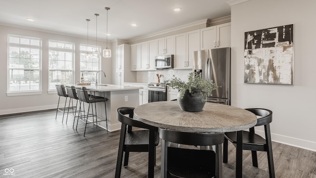 dining area featuring dark wood-type flooring, crown molding, and sink