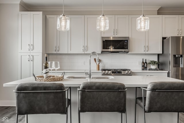 kitchen with light stone counters, stainless steel appliances, white cabinetry, and sink