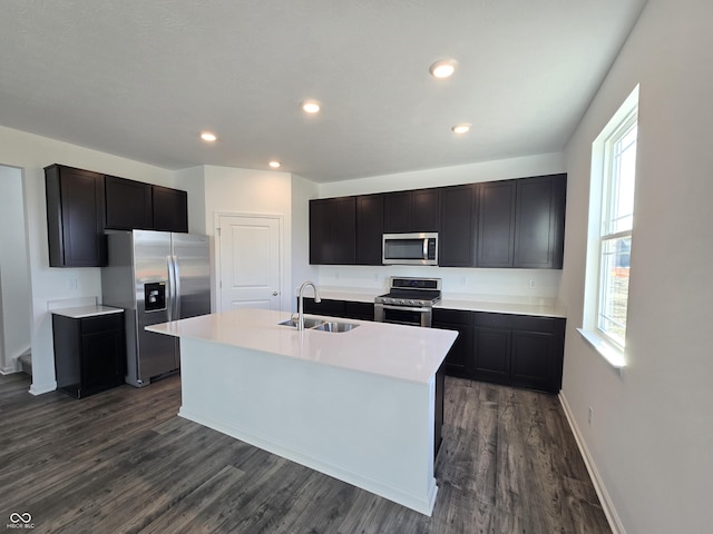 kitchen featuring dark hardwood / wood-style flooring, a kitchen island with sink, sink, and appliances with stainless steel finishes