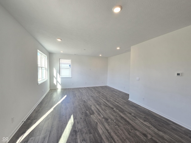 spare room featuring dark wood-type flooring and a textured ceiling