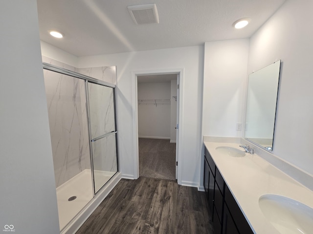 bathroom featuring hardwood / wood-style flooring, vanity, and a shower with door