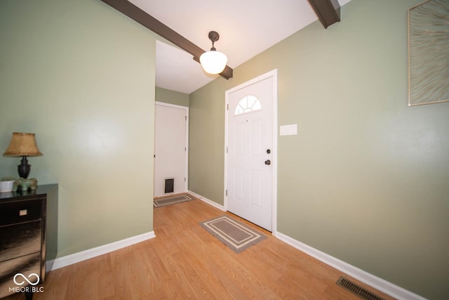 foyer featuring light wood-type flooring and beamed ceiling