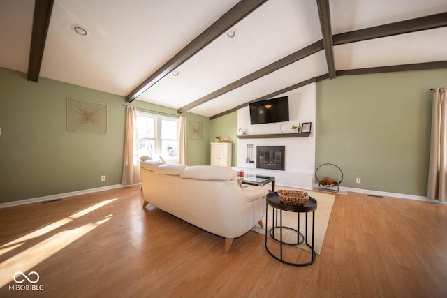 living room with light wood-type flooring, lofted ceiling with beams, and a fireplace