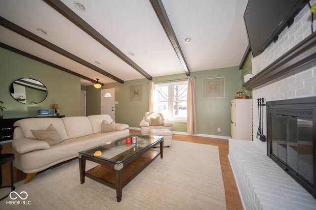 living room with beam ceiling, light hardwood / wood-style flooring, and a brick fireplace