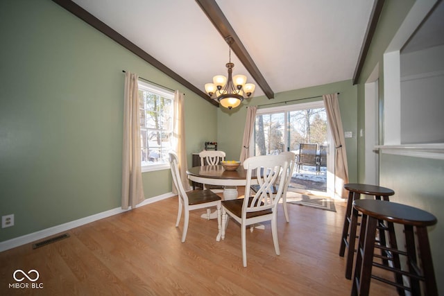 dining space featuring an inviting chandelier, lofted ceiling with beams, a wealth of natural light, and light hardwood / wood-style flooring